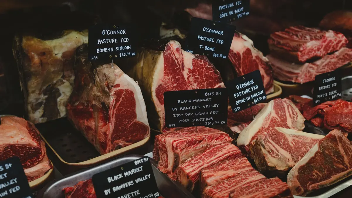 Cortes de carne de res cruda con carteles de precio en la vitrina de una carnicería