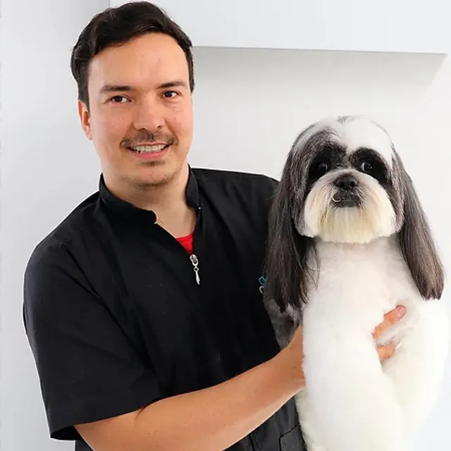 Fabio Gómez Sepúlveda, el instructor del curso, con un perro blanco y gris de orejas largas ya arreglado
