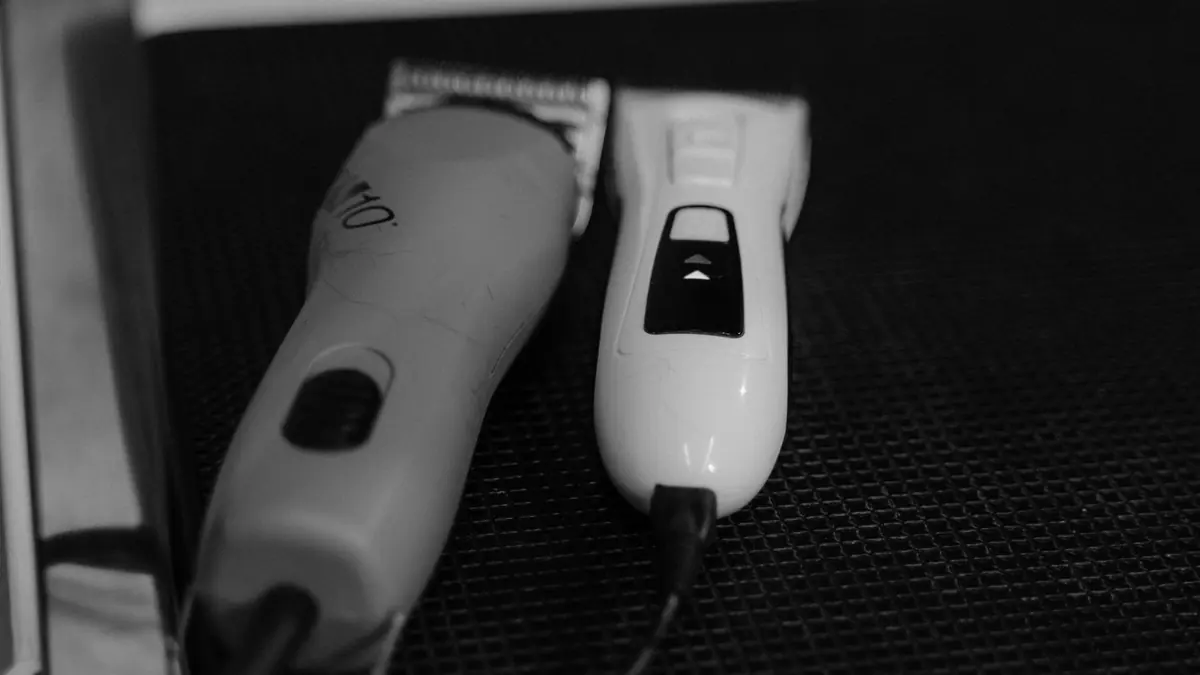Dos máquinas eléctricas de cortar pelo sobre una superficie negra, en blanco y negro