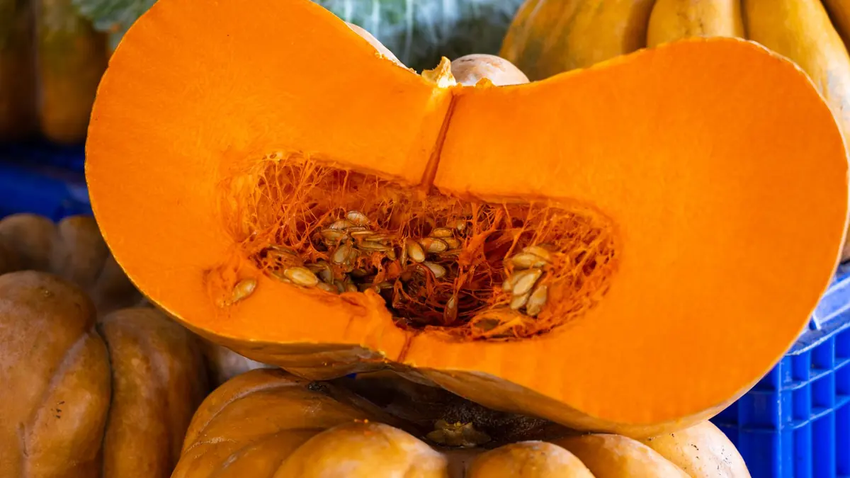Una calabaza cortada por la mitad, con las semillas a la vista, entre otras calabazas