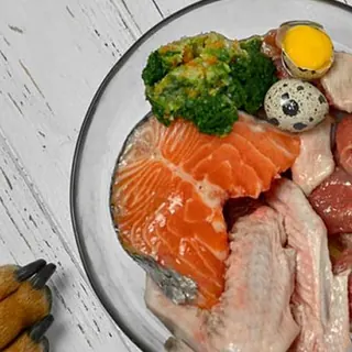 Plato con salmón, alas de pollo, huevo de codorniz y brócoli