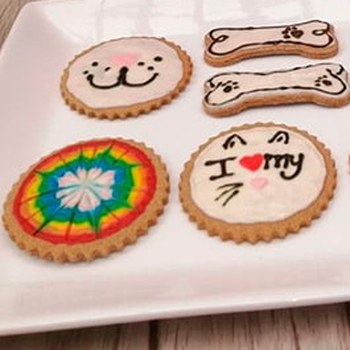 Galletas decoradas, una con la cara de un gato y un corazón, otra con una carita sonriente y dos con forma de hueso